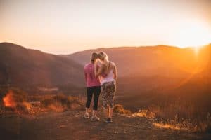 Two girls watching the sunset atop a mountain.