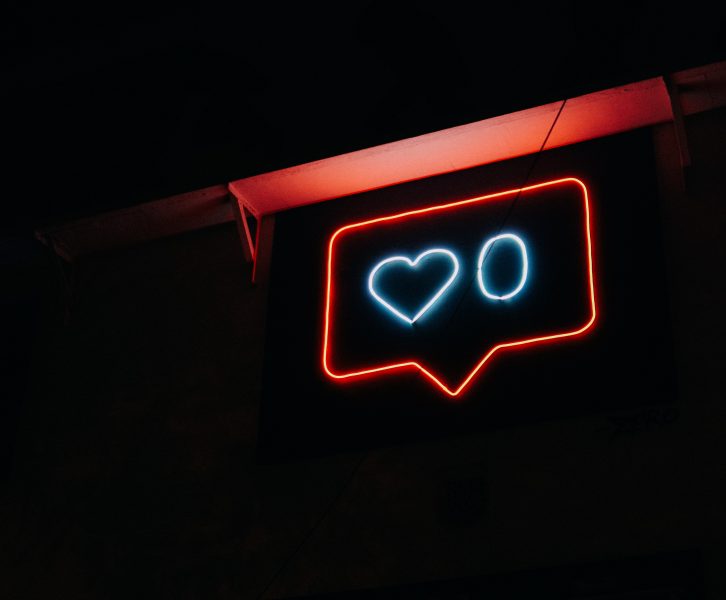 A neon sign showing zero likes on a social media post