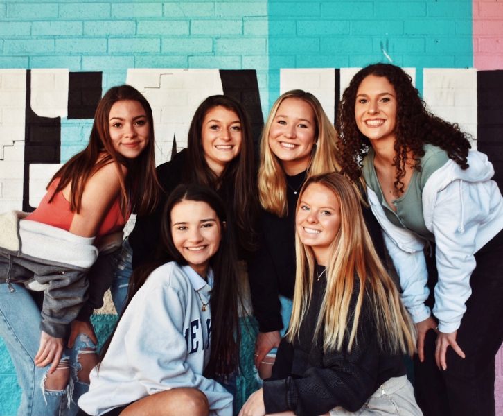 A group of teenage girls pose and smile happily