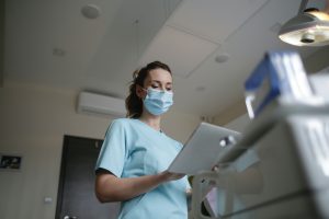An image of a nurse with a medical mask on in a medical building setting. Symbolizes how to navigate health insurance as a young adult.