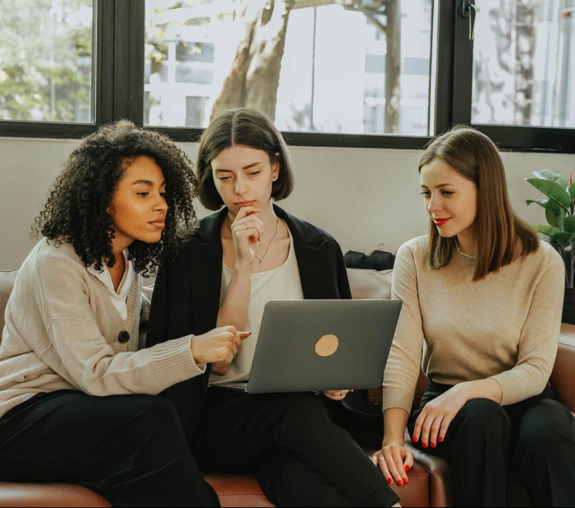 three women looking at a laptop working together