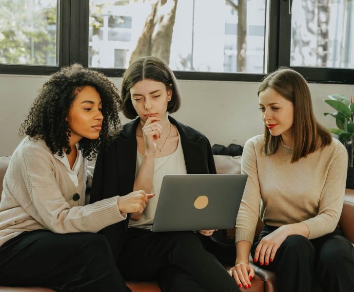 three women looking at a laptop working together