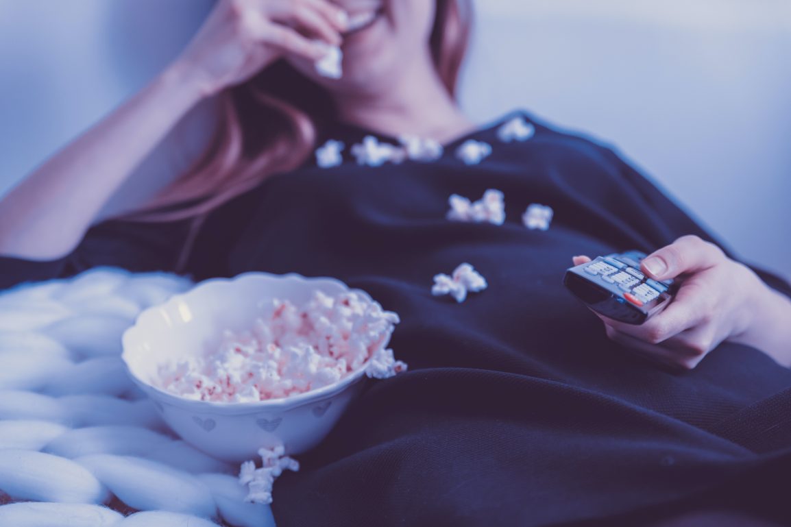 Woman eating popcorn and watching tv