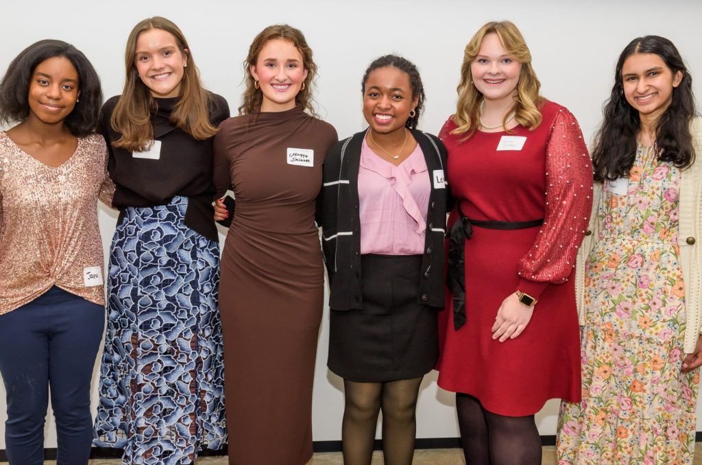 Photo of four young women smiling and standing together in a group, with a sign above them that reads "Meet the Springboarders." The image is related to a Teen Advisory Board.