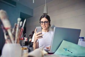 woman in white shirt looking at iphone
