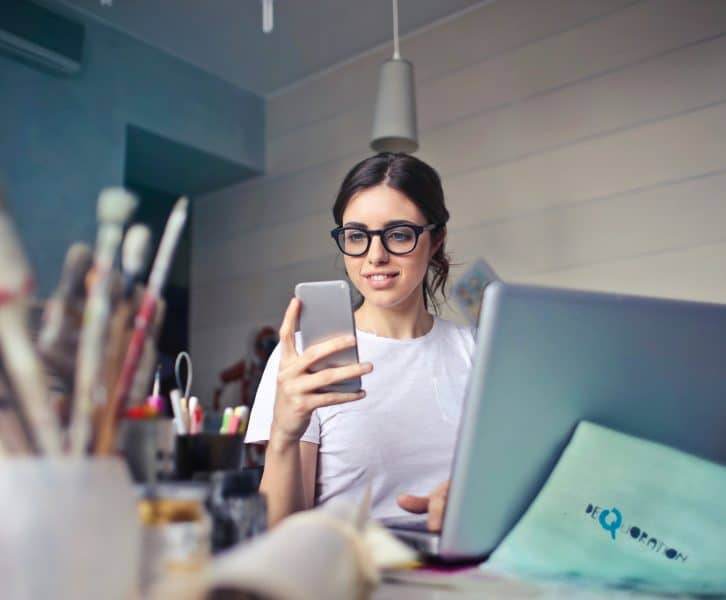 woman in white shirt looking at iphone